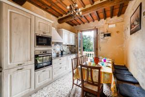a kitchen with white cabinets and a table with chairs at Appartamento Giovanni - Relax Among Green - Happy Rentals in Camaiore