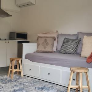 a bedroom with a white bed with two stools at Canyonleigh Retreat in Canyon Leigh