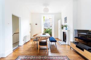 ein Wohnzimmer mit einem Tisch, Stühlen und einem Kamin in der Unterkunft 2-bedroom split-level apartment in Notting Hill in London