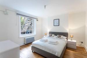 ein weißes Schlafzimmer mit einem großen Bett und einem Fenster in der Unterkunft 2-bedroom split-level apartment in Notting Hill in London