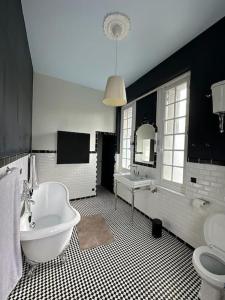 een badkamer met een wit bad, een toilet en een wastafel bij Villa La Clairière in Royan