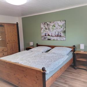 1 dormitorio con cama de madera y una pintura en la pared en Ferienwohnung 1 - a76809, en Groß Vollstedt