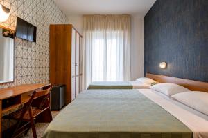 una camera d'albergo con 2 letti e una scrivania di Hotel Atlas a Rimini