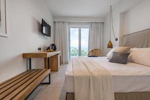 Schlafzimmer mit einem Bett, einer Bank und einem Fenster in der Unterkunft Amaronda Resort & Spa Eretria in Eretria