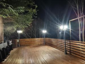 a wooden deck with two lights on a fence at night at SEZATOAREA LUPILOR in Lepşa