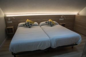 duas camas num quarto de hotel com lençóis brancos em Posada de Roncesvalles em Roncesvalles