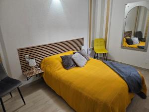1 dormitorio con cama amarilla y silla amarilla en Bono plages récemment rénové février 2024, en Mèze