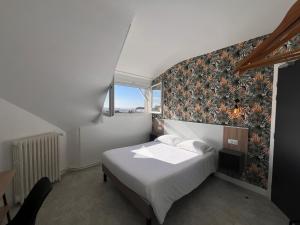 Un dormitorio con una cama con una pared de acento floral en Hôtel Le Keroman, en Lorient