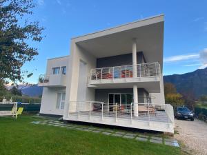a large white house with a balcony and a car at B&B A Un Passo Dal Lago, Caldonazzo in Caldonazzo