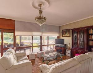 una sala de estar con muebles blancos y una lámpara de araña. en Casa Ana De Velasco, en Marcilla