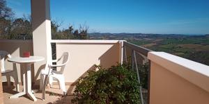 balcón con mesa, silla y vistas en Appartamento Che Vista! Affittacamere, en Mombaroccio