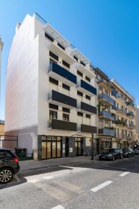 - un bâtiment blanc avec des balcons noirs dans une rue dans l'établissement Lusíadas 53 2ºD - Beautiful two-bedroom apartment, à Lisbonne