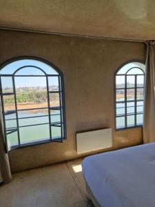 two windows in a room with a bed and water at L'Oum Errebia in Azemmour