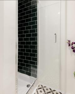 y baño con ducha y pared de ladrillo negro. en Spacious & stylish 1-bed flat in Primrose Hill en Londres