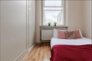 Habitación blanca pequeña con cama y ventana en Spacious & stylish 1-bed flat in Primrose Hill en Londres