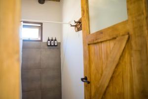 a bathroom with a wooden door and a shower at Loma Puskana - Casas in Cachí