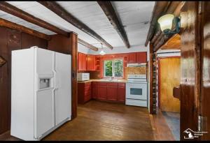 a kitchen with red cabinets and a white refrigerator at Restored historic log cabin & deck on Lake Erie in Luna Pier