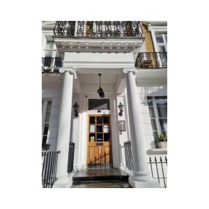 a white house with a wooden door and columns at G3- Great Studio for 2 with Patio near Hyde Park in London