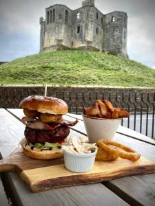a sandwich and fries on a cutting board with a castle at The Sun Hotel in Warkworth