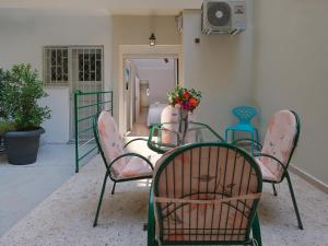 une table avec des chaises et une table avec un vase de fleurs dans l'établissement AnapironPolemou5-Eleutheriou, à Athènes