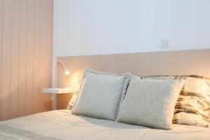 a bed with white sheets and pillows in a bedroom at L'Escale cosy, proche Euroairport in Saint-Louis