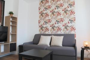 a living room with a couch and a floral curtain at L'Escale cosy, proche Euroairport in Saint-Louis