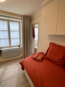 1 dormitorio con cama con sábanas de color naranja y ventana en Comme une chambre d’hôtel au cœur de Lyon, en Lyon