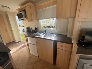 a small kitchen with a sink and a window at 2 Bedroom Caravan Stay, Central Beach, Leysdown in Leysdown-on-Sea