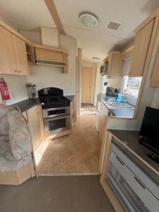 a small kitchen with a stove and a sink at 2 Bedroom Caravan Stay, Central Beach, Leysdown in Leysdown-on-Sea