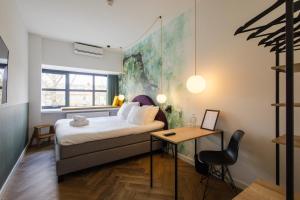 a bedroom with a bed and a desk with a chair at Badhuis Hotel in Utrecht