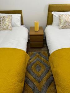 sypialnia z 2 łóżkami z żółtymi kocami i stołem w obiekcie Stunning 3-Bed House in Manchester w Manchesterze