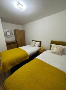 dwa łóżka z żółtą pościelą w pokoju w obiekcie Stunning 3-Bed House in Manchester w Manchesterze