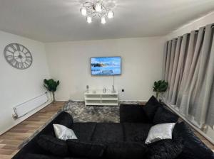 a living room with a black couch and a clock at Stunning 3-Bed House in Manchester in Manchester