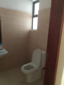 a bathroom with a white toilet and a window at Studio Apartment Nyali in Mombasa
