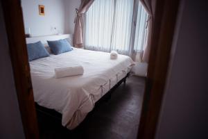 Schlafzimmer mit einem Bett mit weißer Bettwäsche und blauen Kissen in der Unterkunft Loma Puskana - Casas in Cachí