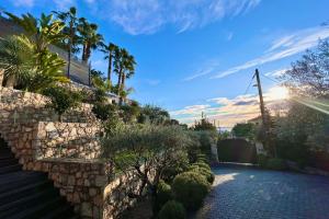 um jardim com palmeiras e uma parede de pedra em Golfe-Juan - Villa 10 people - Private Pool - Parking em Vallauris