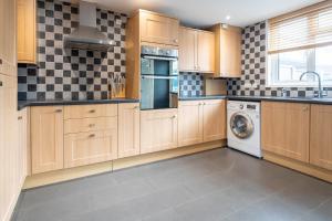 a kitchen with wooden cabinets and a washer and dryer at Gatwick Place - 4 bed 2 bath self contained house with private garden in Horley