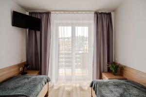 - une chambre avec 2 lits et une grande fenêtre dans l'établissement Centrum Wypoczynku i Rekreacji Rysy Krynica Zdrój, à Krynica-Zdrój