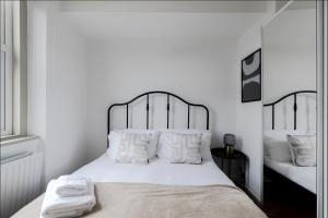 a white bedroom with a large bed with white pillows at Primrose Hill Charming 1-Bed Flat in London