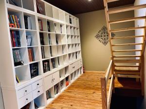 una habitación con estanterías de libros blancos y una escalera en Les Volets Blancs en 's-Gravenbrakel
