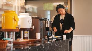 Una donna in piedi in una cucina che prepara il cibo di Zhangjiajie Hero Boutique Hotel a Zhangjiajie