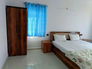 a bedroom with a bed and a blue curtain at Zanita Heights Seaview Apt in Bogmalo