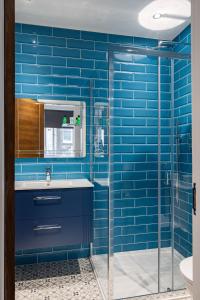 a blue tiled bathroom with a sink and a shower at Edgware road apartments in London