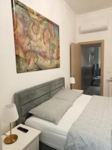 a bedroom with a bed and a painting on the wall at Fenix Rooms in Trieste