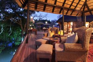 a wooden deck with chairs and tables and an umbrella at Ndlovu Safari Lodge in Welgevonden Game Reserve