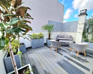 an outdoor deck with plants and a couch at Le Rooftop Suresnes Paris La Défense - Spacieux Duplex 100 m2 Terrasse in Suresnes