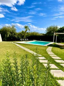 a garden with a swimming pool and a grass field at Strelitzia's house with heated pool , private garden and private parking & wi-fi in Avola
