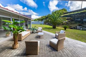 un patio con sedie e tavoli in vimini e una pianta di Luxury Villa in Ribeira Grande a Ribeira Grande