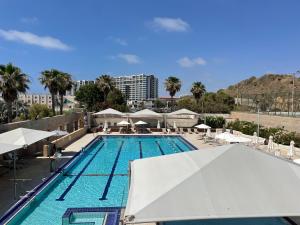 una piscina con sombrillas blancas y un complejo en מלון דירות אוקיינוס במרינה דירות עם נוף לים en Herzliyya B