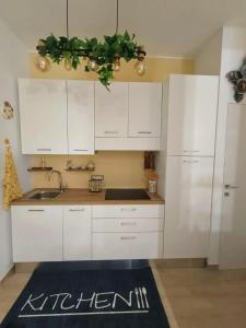 eine Küche mit weißen Schränken und einem Küchenteppich in der Unterkunft The Cavern - Salento da aMare in Casarano
